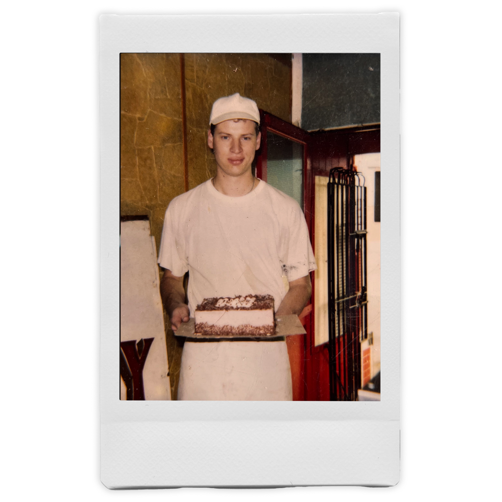 Fotografía instantánea del pastelero joven sosteniendo un pastel