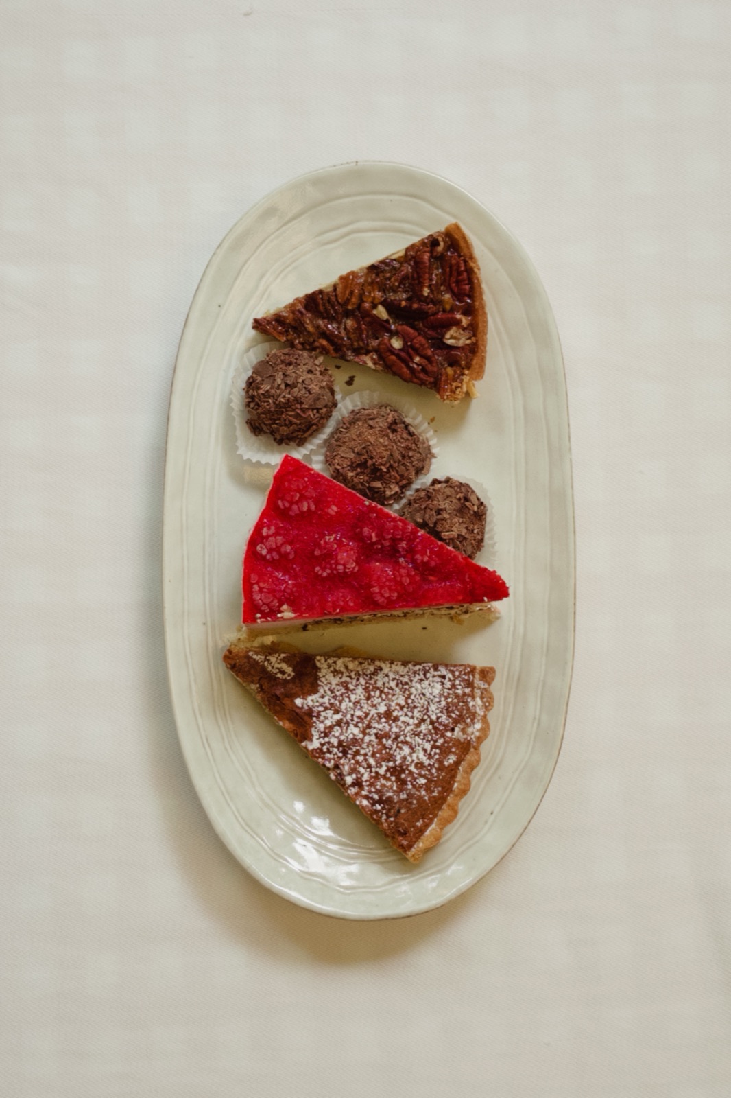 Plato con porciones de pie de pecanas, mousse de frambuesa, torta de Santiago y trufas